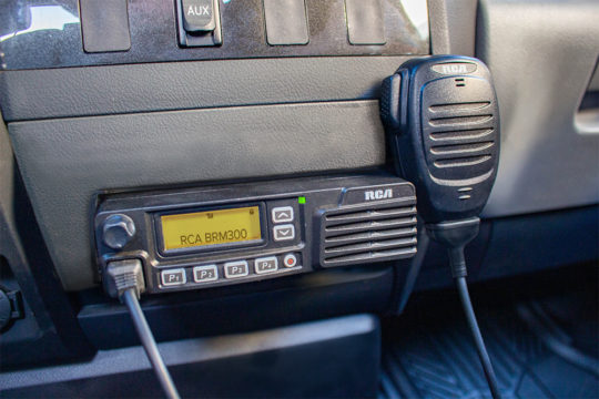 An RCA BRM300D mobile two-way radio is mounted to a vehicle's center console.